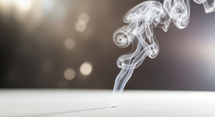 Wisps of smoke curl upwards against a blurred, bokeh background