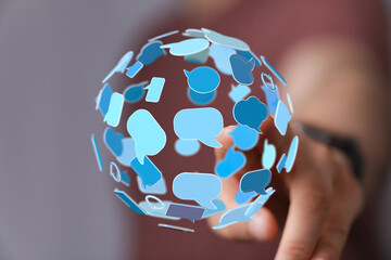 Hand reaching for a digital sphere of speech bubbles, representing global communication and connectivity on the Internet.