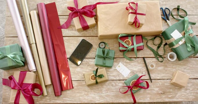 camera starting recording top down over wooden table showing wrapping tools and gifts for gifting