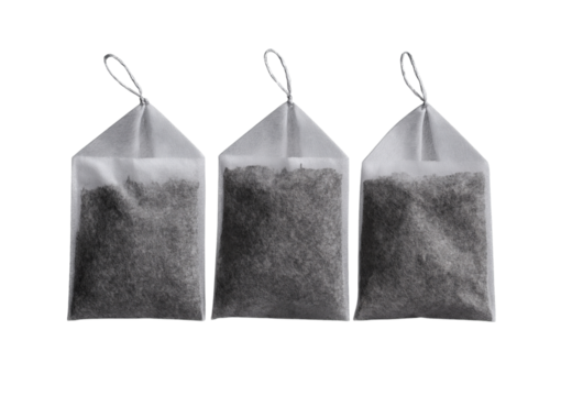 Three white tea bags with dark tea leaves isolated on a transparent background