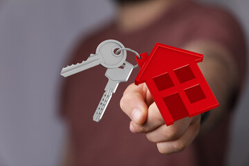 Hand holding house key chain and keys, symbolizing home ownership, security, real estate, and the...