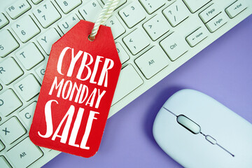 Price tag with text "Cyber Monday Sale " and white keyboard and wireless mouse on purple background