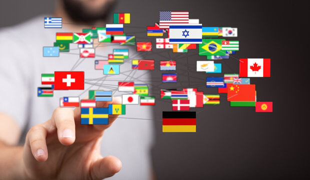 Hand reaching out to diverse flags, representing connection, global unity, international collaboration, and technology. A visual representation - Powered by Adobe