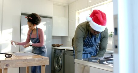 couple picking up spray can and starting baking tray coating in kitchen, prepping holiday treats