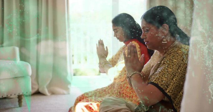 Mother and daughter joining palms, bowing heads, praying while green overlay drifting across frame