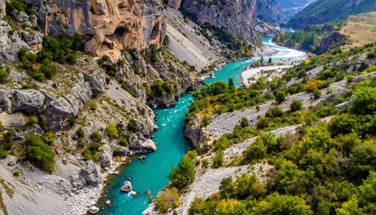 A vibrant turquoise river snakes through a rugged canyon with rocky cliffs and lush green vegetation on either side