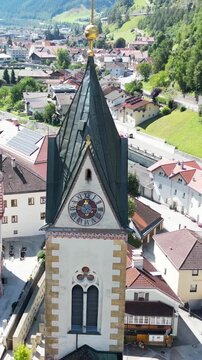 church steeple detail in austria near brenner pass scenic small town in the alps with mountain background river train tracks alpine village christian cross top colorful white drone footage scene 