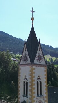 church steeple detail in austria near brenner pass scenic small town in the alps with mountain background river train tracks alpine village christian cross top colorful white drone footage scene 