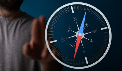 Fototapeta premium A person's finger pointing towards a compass, symbolizing navigation, direction, and guidance. Concept of finding your way, achieving goals and