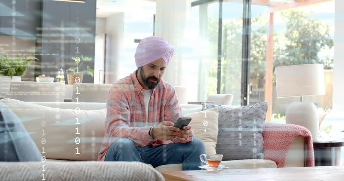 mid-adult man sofa tapping phone, browsing tech, binary overlay appearing, placing phone by teacup