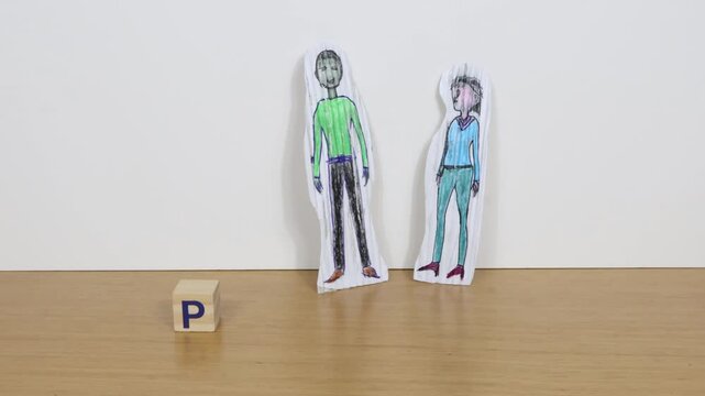 Word pension composed of wooden blocks, on the table a couple of cardboard silhouettes.