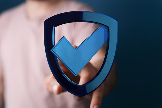 A person's hand touches a digital shield icon with a checkmark, representing data protection, cyber security, and security verificati