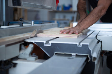 Ein Handwerker schneidet eine Holzplatte mit einer Kreissäge in einer Werkstatt. Fokus auf die...