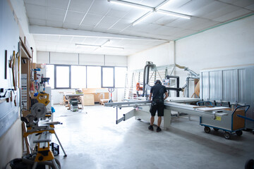 Moderne Werkstatt mit Holzbearbeitungsmaschinen und Handwerker bei der Arbeit