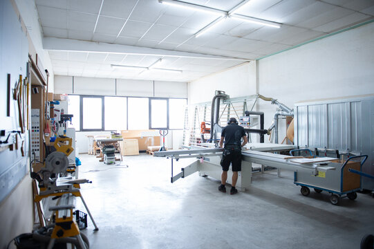 Moderne Werkstatt mit Holzbearbeitungsmaschinen und Handwerker bei der Arbeit