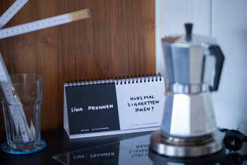 Kaffeekocher, Notizaufsteller und Glas mit Zollstock auf K&uuml;chentisch