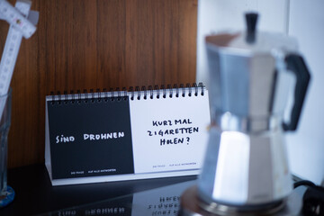 Kaffeekocher, Notizaufsteller und Glas mit Zollstock auf K&uuml;chentisch