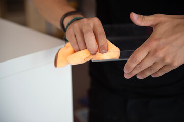 Hand reinigt Glasplatte mit Mikrofasertuch, Nahaufnahme beim Putzen