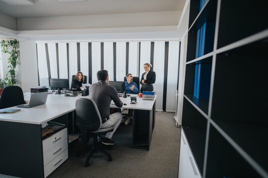 A group of professionals collaborating in a modern office with computers and documents, creating a productive work environment for team discussions and effective decision-making.