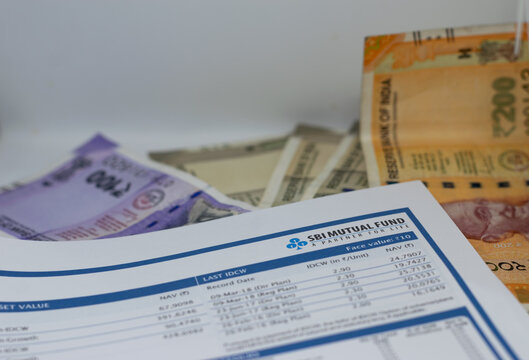 Currency notes, coins and an SBI Mutual Fund sheet showcasing NAV details, financial planning elements and investment insights for investors tracking market performance and evaluating portfolio growth