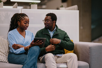 Business colleagues collaborating on tablet in office lounge