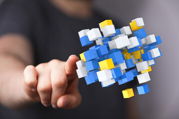 A person's finger pointing at a vibrant cluster of colorful 3D cubes. Concepts of connection, the digital world