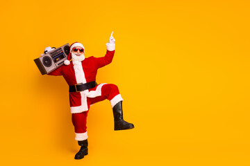 Santa Claus with a boombox dancing against a bright yellow background celebrating Christmas and New...