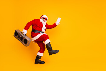 Santa with a boombox jumps in a bright yellow studio waving hello celebrating Christmas and New Year cheer