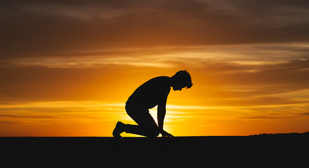 Silhouette of Kneeling Person Against a Golden Sunset