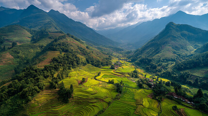Aerial view of green rice terraces in a valley surrounded by mountains under a cloudy blue sky