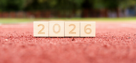 Blocks show the year 2026 on a bright track, symbolizing the new year ahead. Friends gather to celebrate with laughter and cheer, embracing the festive spirit of the season