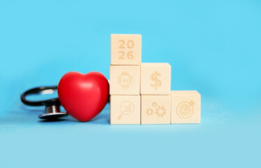 Blocks representing 2026, health, and financial growth are arranged with a red heart and a stethoscope, symbolizing love and wellness for the upcoming New Year