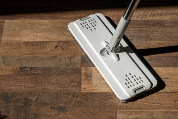 Top view of a flat microfiber mop on a wooden floor in natural light
