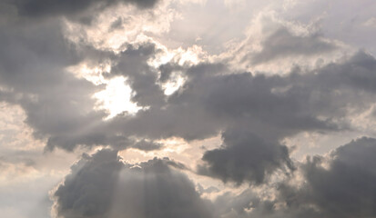 An evening dramatic golden hour sky background with clouds and soft sun rays breaking through.