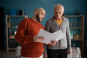 Accounting, finance or refund, mortgage and tax. Senior father with adult son in home reading documents for bank payment.
