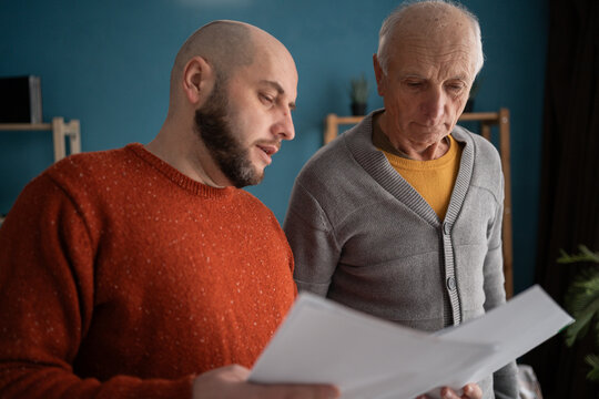 Accounting, finance or refund, mortgage and tax. Senior father with adult son in home reading documents for bank payment.