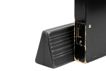 Black door wedge holding open a weathered black door isolated on a transparent background