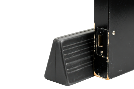 Black door wedge holding open a weathered black door isolated on a transparent background