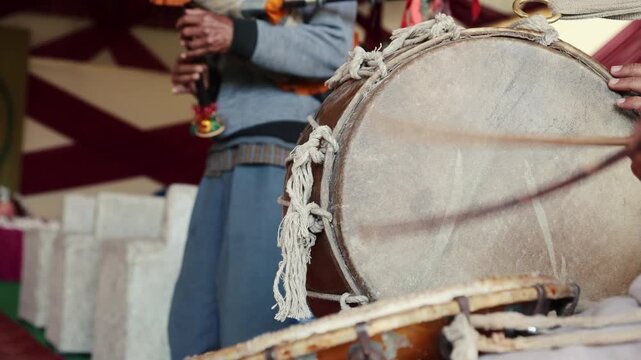4K footage of Indian village musicians performing dhol and bagpipe during a marriage ceremony. Rhythmic drum beats and folk tunes create an authentic festive atmosphere in rural Uttarakhand.