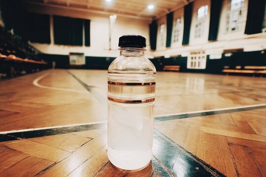 Minimalistic water bottle stands on polished gym floor, highlighting hydration importance
