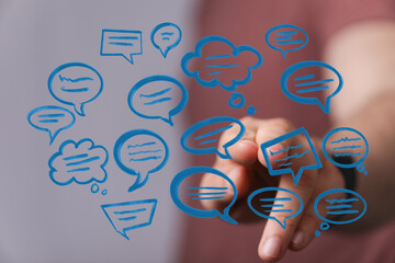 Person's hand touching digital speech bubbles, a visual representation of communication, messaging, and online