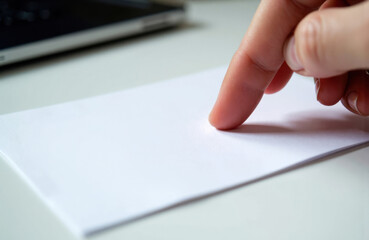 A person’s finger touches a blank sheet of paper on a desk