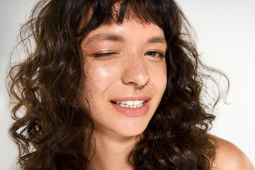 Young woman in stylish attire winks playfully with a confident and joyful expression