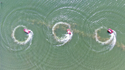 Red Motorboats Making Circular Loops in Green Water - Aerial View
