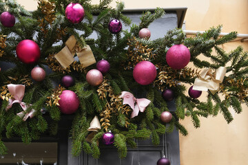 The golden bow on a Christmas tree branches with purple balls