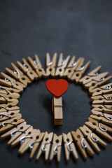 Heart-Shaped Clothespin in Center of Circle Formed by Neutral Clothespins on Dark Background