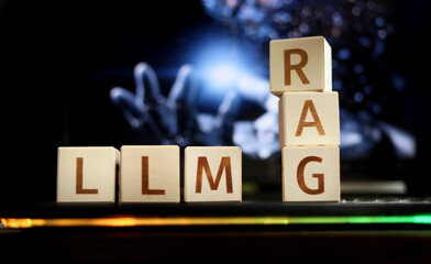 Wooden blocks display the letters LLM and RAG against a dark and abstract background, emphasizing the connection between technology and innovative language models in a creative setup