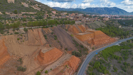 Fototapeta premium Ruins of the Monteponi Mining District with Red Waste Deposits