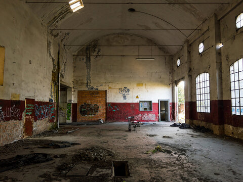 Empty industrial warehouse in ruins featuring aged architecture urban decay textures and moody light representing forgotten factory environment. - Powered by Adobe