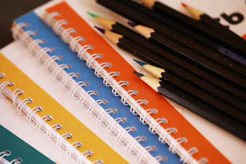 Colorful Spiral Notebooks and Black Pencils: Creative Desk Essentials for Students and Artists